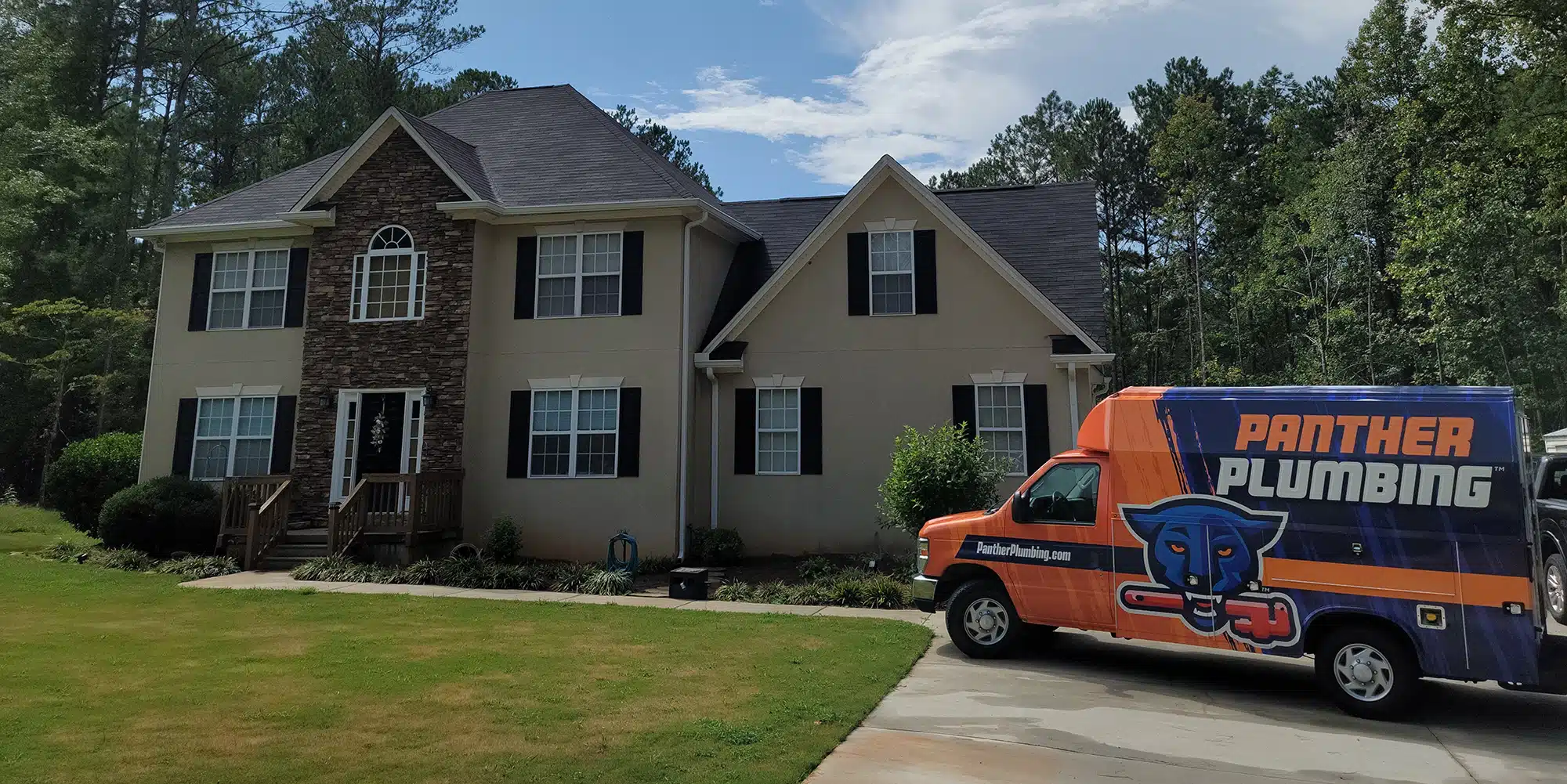 The Panther Plumbing truck parked in the driveway of a residential home in Austell, GA.