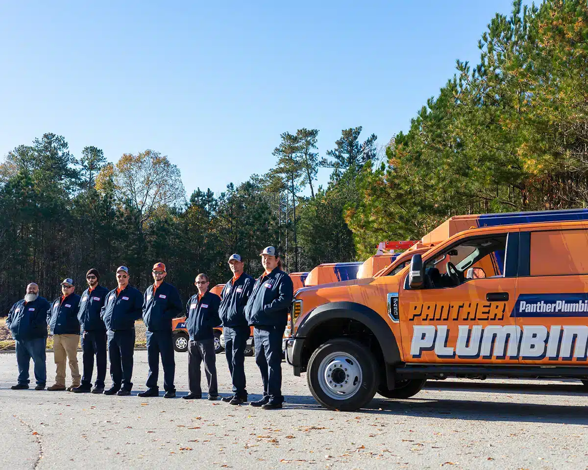 The Panther Plumbing team of experts in front of their fleet of trucks.