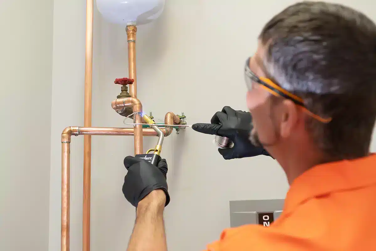 A Panther Plumbing technician soldering copper pipe in Austell, GA.