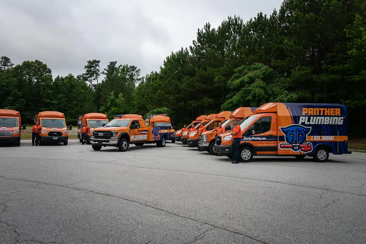 The Panther Plumbing team of experts in front of their fleet of trucks.